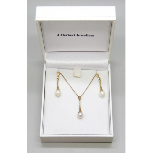 7162 - A 9ct gold chain with a yellow metal cultured pearl drop pendant, 2.2cm, and a pair of matching yell... 