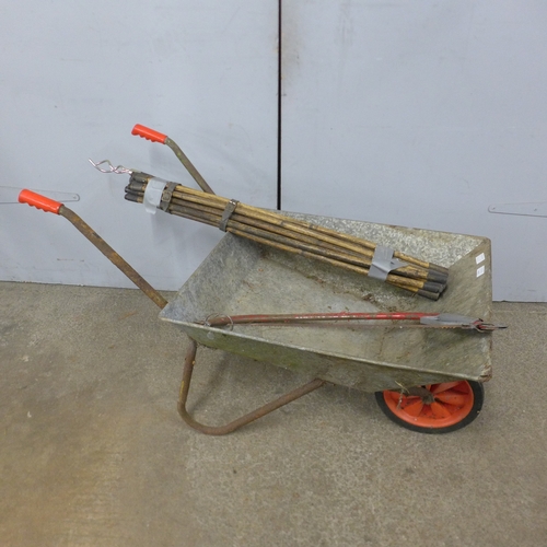 5244 - A metal wheelbarrow with drain rods and saw