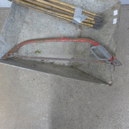 5244 - A metal wheelbarrow with drain rods and saw
