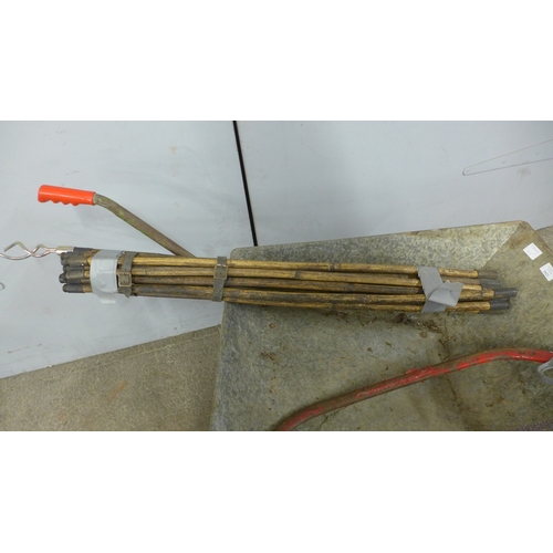 5244 - A metal wheelbarrow with drain rods and saw