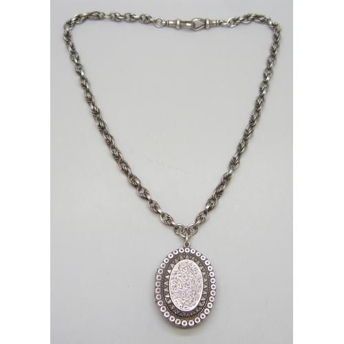 7133 - A Victorian silver locket, on a silver rope design Albert chain with two dog clips, each link marked... 