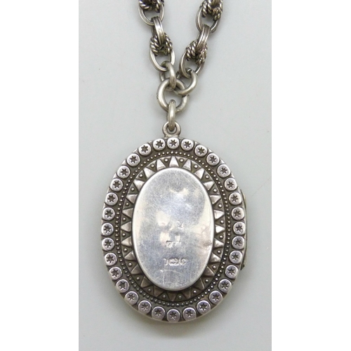 7133 - A Victorian silver locket, on a silver rope design Albert chain with two dog clips, each link marked... 