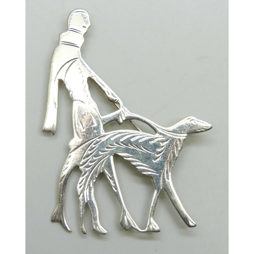 7082 - An Art Deco style silver brooch in the form of a lady walking a dog, 6.6cm