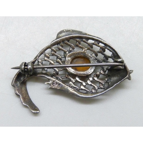 7147 - A silver brooch in the form of a fish, set with Baltic amber, 3.6cm