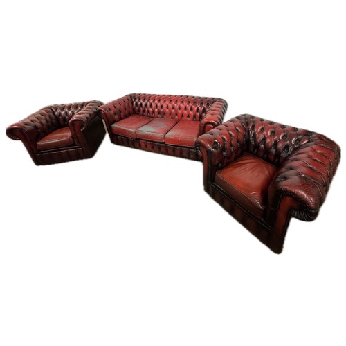 102 - An oxblood red leather Chesterfield  three piece lounge suite, comprising; three seater settee and p... 