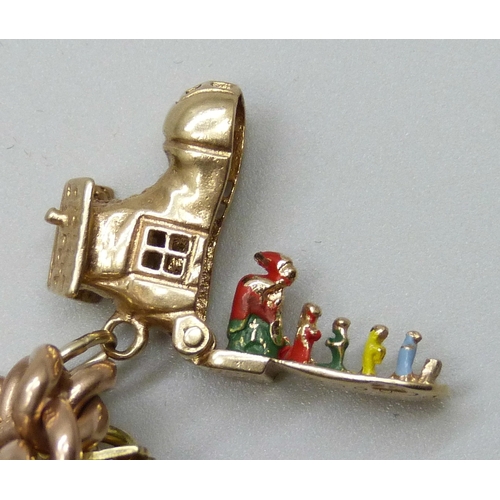 7092 - A 9ct gold curb chain charm bracelet with a collection of charms - ten 9ct gold charms, an 18ct gold... 