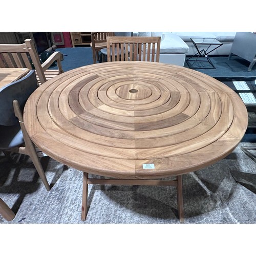 3040 - A teak circular folding garden table and a pair of teak carver chairs
