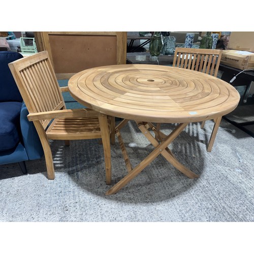 3040 - A teak circular folding garden table and a pair of teak carver chairs