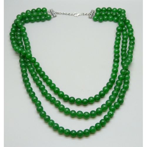 7124 - A three strand green stone necklace with a plated clasp, 136g