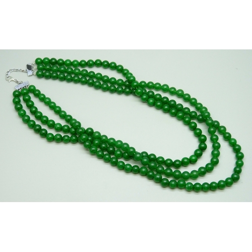 7124 - A three strand green stone necklace with a plated clasp, 136g