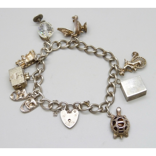 7140 - A white metal charm bracelet with a silver clasp, and a collection of silver and white metal charms,... 