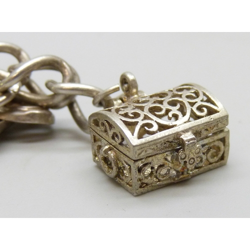 7140 - A white metal charm bracelet with a silver clasp, and a collection of silver and white metal charms,... 