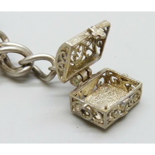 7140 - A white metal charm bracelet with a silver clasp, and a collection of silver and white metal charms,... 