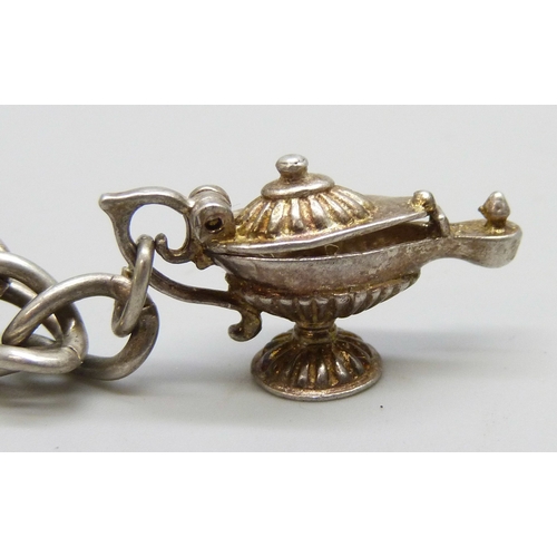 7140 - A white metal charm bracelet with a silver clasp, and a collection of silver and white metal charms,... 