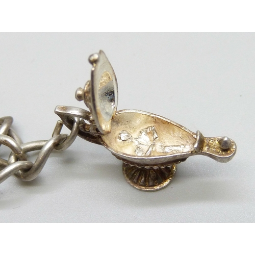 7140 - A white metal charm bracelet with a silver clasp, and a collection of silver and white metal charms,... 