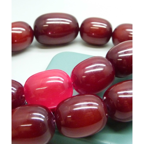 7079 - A very large cherry amber coloured bead necklace, largest bead approximately 4cm, 198g, 53cm