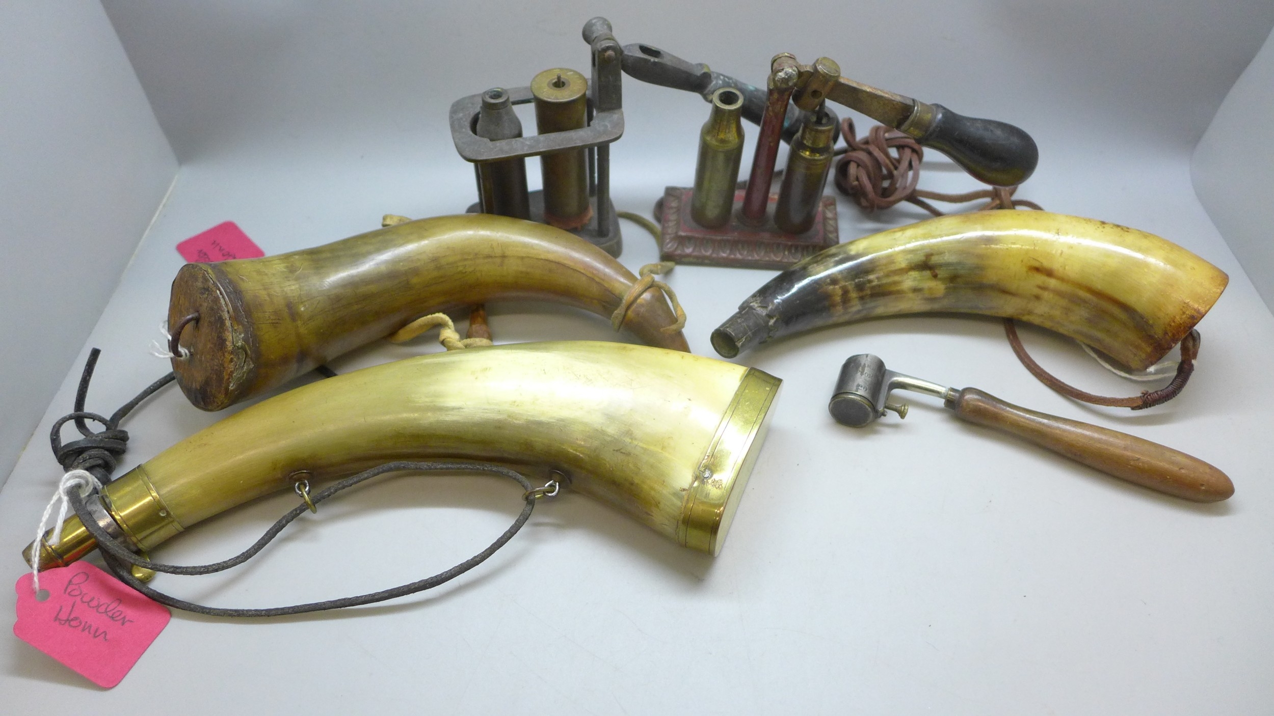 A brass mounted horn powder flask, two other horn powder flasks, a ...