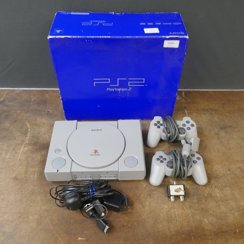 A PlayStation games console with two controllers and power cable in a ...
