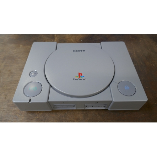 A PlayStation games console with two controllers and power cable in a ...