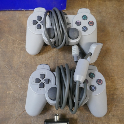A PlayStation games console with two controllers and power cable in a ...