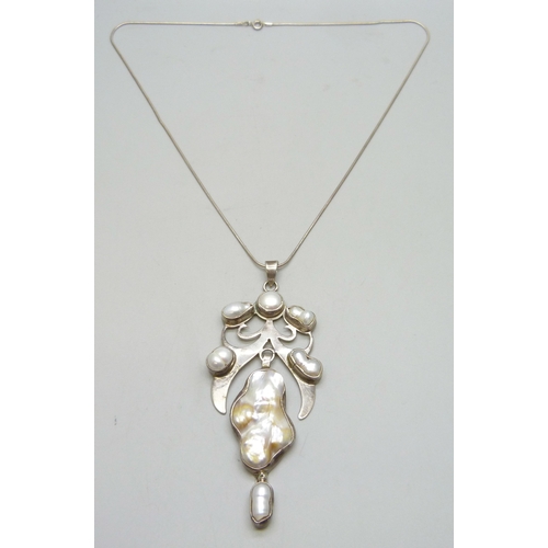 7162 - An Arts and Crafts style silver and baroque pearl statement  pendant, 10.5cm including bail, on a si... 