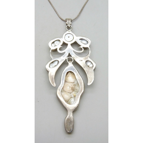 7162 - An Arts and Crafts style silver and baroque pearl statement  pendant, 10.5cm including bail, on a si... 