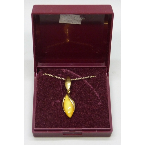 7165 - A silver gilt egg yolk amber pendant, 3.5cm, on a gilt chain, boxed