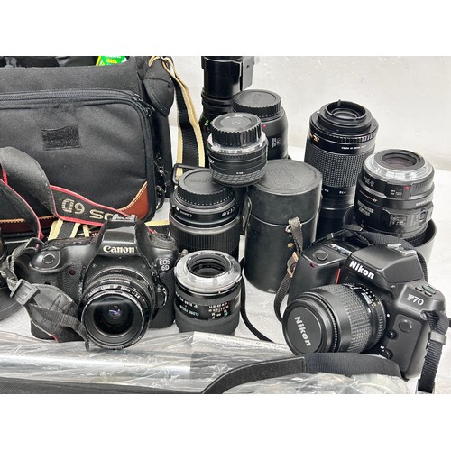 2294 - A large quantity of lenses and a Canon camera body, together with stands