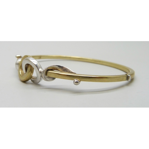 7001 - A 9ct white and yellow gold bangle with interlocking loop design, 7.4g, 6 x 5cm
