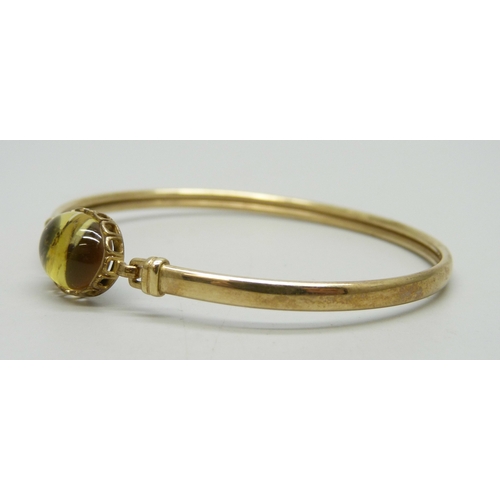 7054 - A 9ct gold bangle, the cabochon a/f, 4.9g, 5.8 x 5.1cm