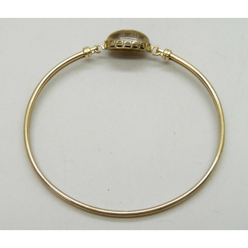 7054 - A 9ct gold bangle, the cabochon a/f, 4.9g, 5.8 x 5.1cm