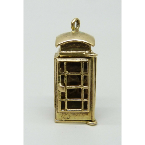 7002 - A 9ct gold charm in the form of a telephone box, the door opens to reveal the interior, hallmarked, ... 