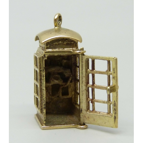 7002 - A 9ct gold charm in the form of a telephone box, the door opens to reveal the interior, hallmarked, ... 