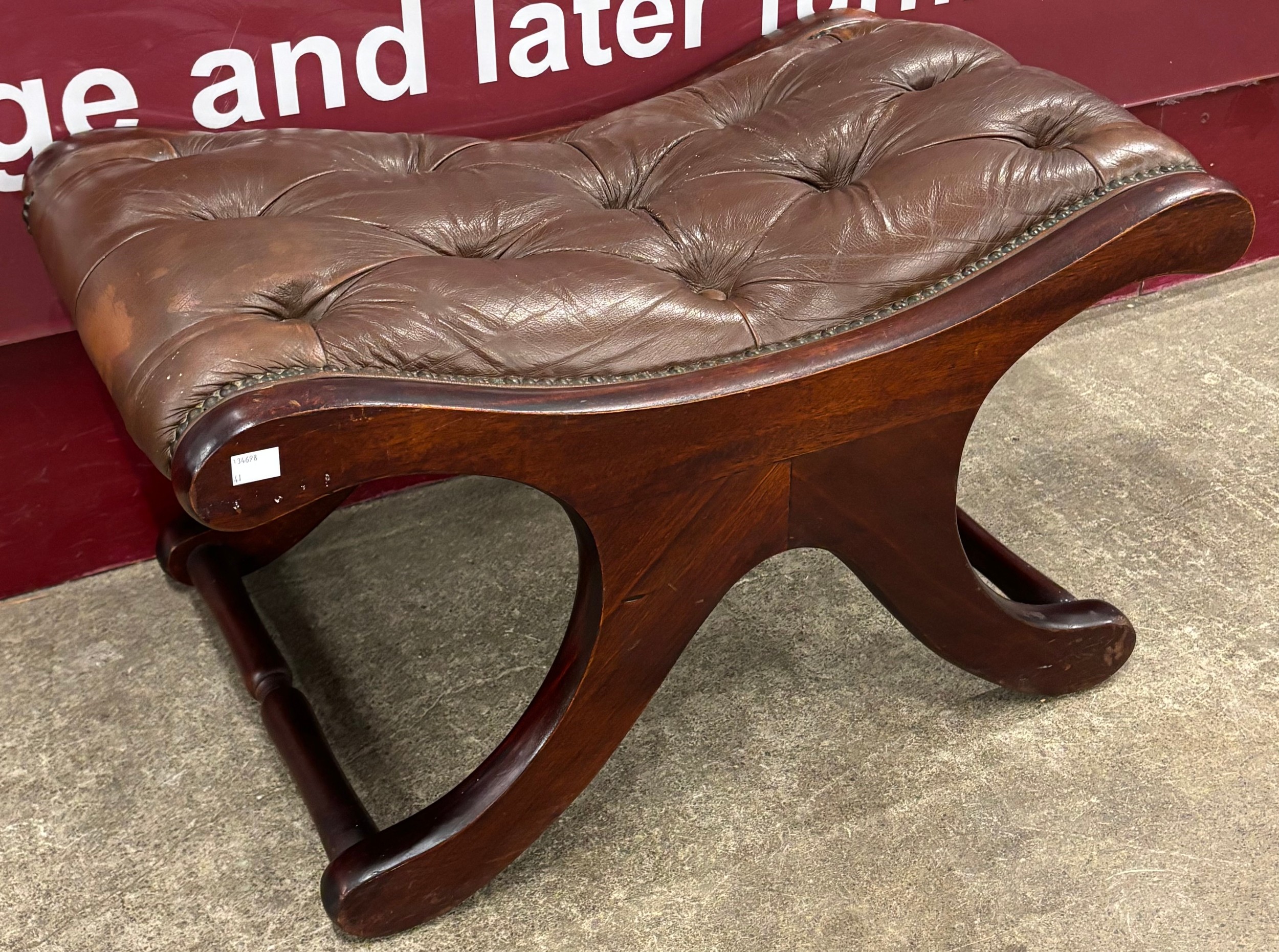 A Regency style chestnut brown leather Chesterfield saddle stool