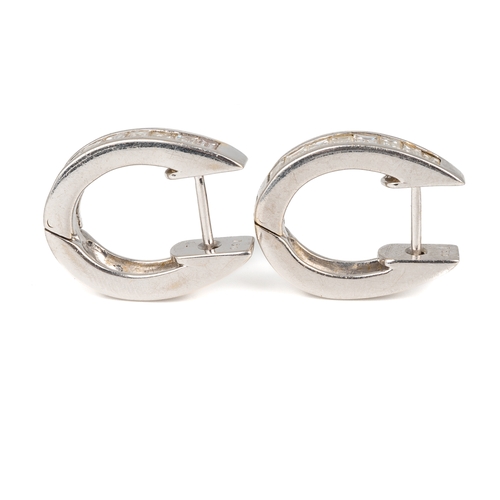 66 - A pair of 18k white gold and diamond huggie hoop earrings, each channel set with eight baguette-cut ... 