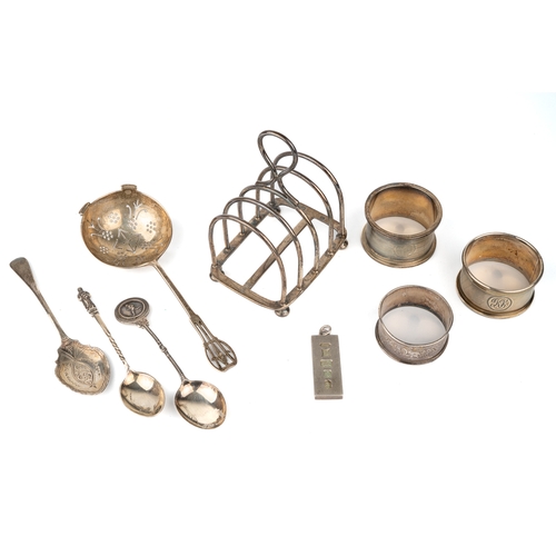 182 - A collection of silver, including a five-bar toast rack; three napkin rings; a straining spoon; and ... 