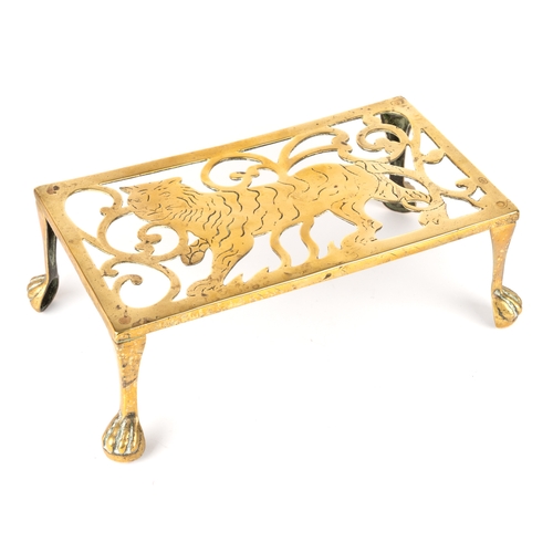 319 - A 19th century rectangular brass trivet, depicting a tiger, raised on four legs with paw feet, appro... 