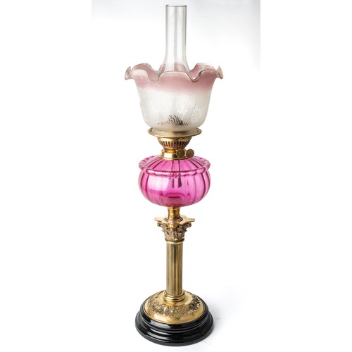 620 - A Victorian oil lamp with a black porcelain base with brass fittings and fluted cranberry  glass bod... 