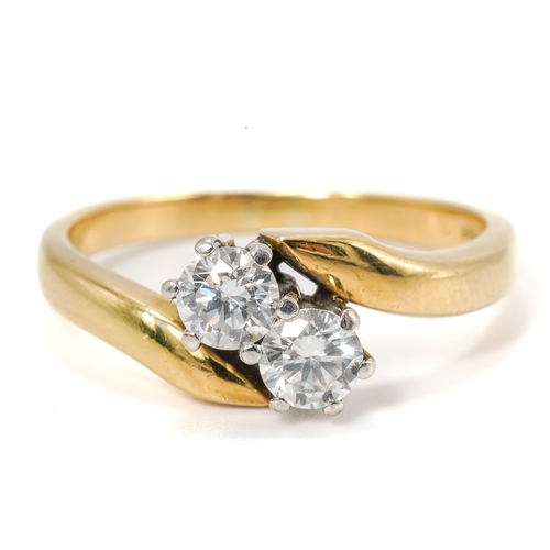 13 - An 18ct yellow gold and diamond two stone crossover ring, set with round brilliant cut diamonds, eac... 