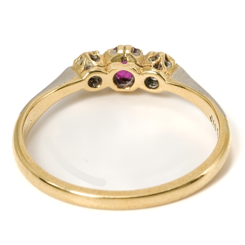 21 - An 18ct yellow gold ruby and diamond three-stone ring, the oval mixed-cut ruby flanked by diamond ch... 