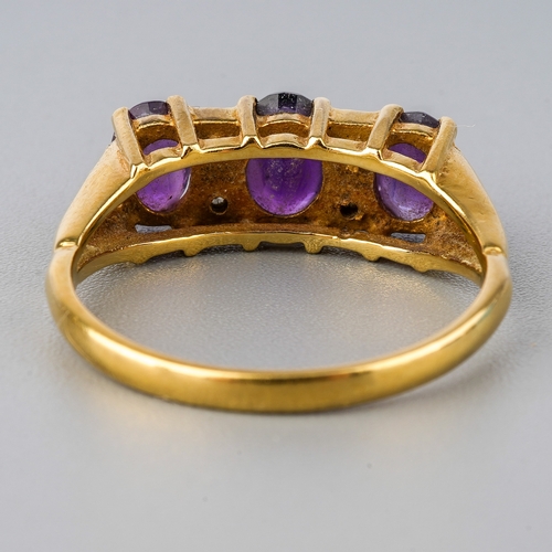 30 - An 18ct yellow gold and amethyst three-stone ring, set with three oval mixed-cut amethyst, diamond c... 