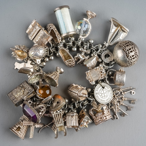 90 - A silver charm bracelet, various assorted charms on a fancy-link bracelet, total gross weight approx... 