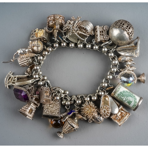 90 - A silver charm bracelet, various assorted charms on a fancy-link bracelet, total gross weight approx... 