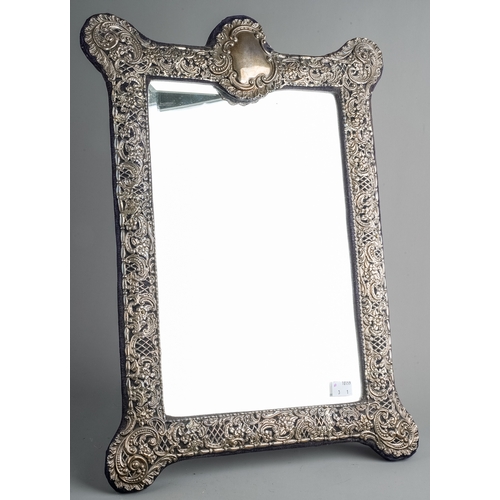 132 - A large Edwardian silver mounted shaped rectangular easel mirror, the embossed and pierced foliate s... 