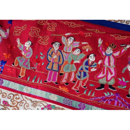 A Chinese embroidered silk wall hanging, the central section with central seated Deity and child under pagoda with attendants, withing panels of motif or floral decoration, tassels to base, signed, the panel approx 190 x 49cm