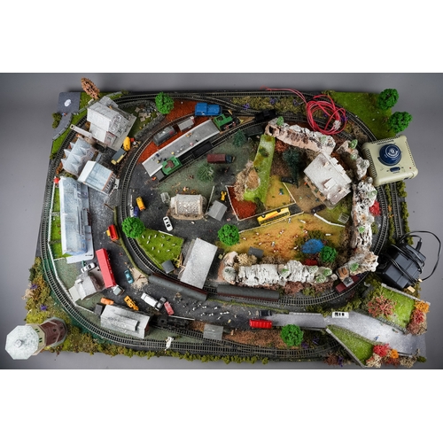 299 - A model railway N gauge train layout fixed on board, the diorama features wintery village scene with... 