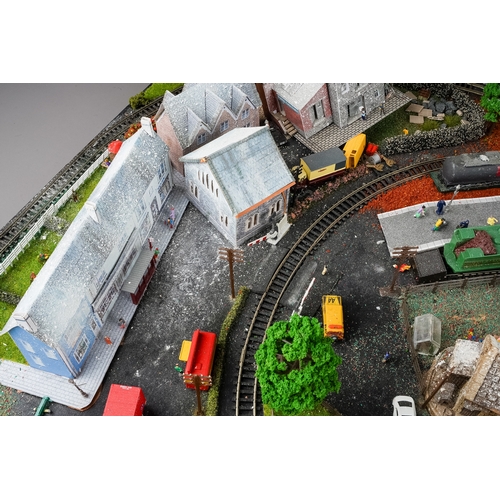 299 - A model railway N gauge train layout fixed on board, the diorama features wintery village scene with... 