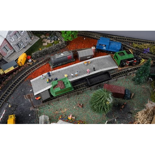 299 - A model railway N gauge train layout fixed on board, the diorama features wintery village scene with... 