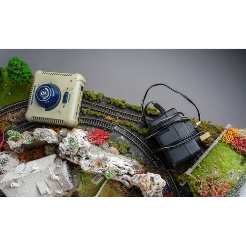 299 - A model railway N gauge train layout fixed on board, the diorama features wintery village scene with... 