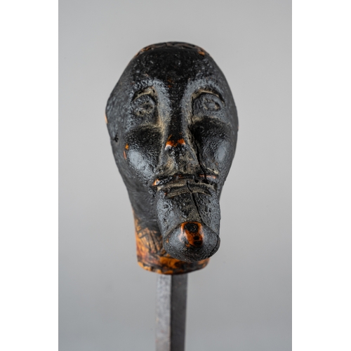 344 - An unusual tribal carved sword stick, in the form of a man with something in his mouth, incised carv... 